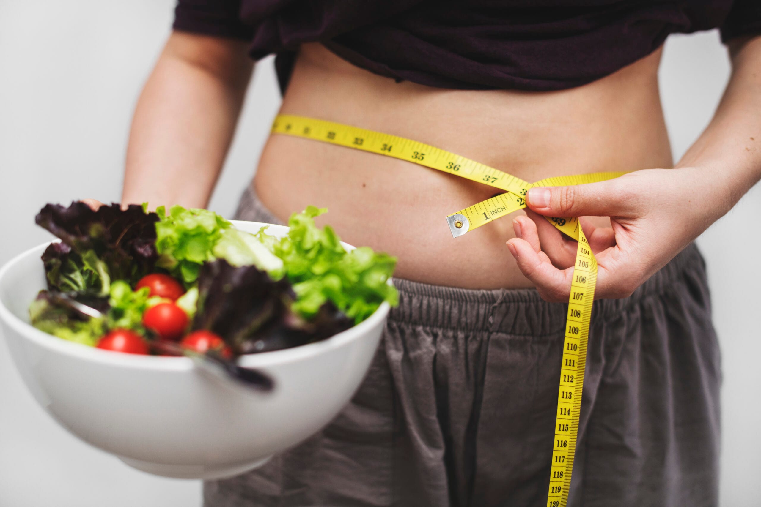 Woman measuring her tummy and weight Woman measuring her tummy and weight