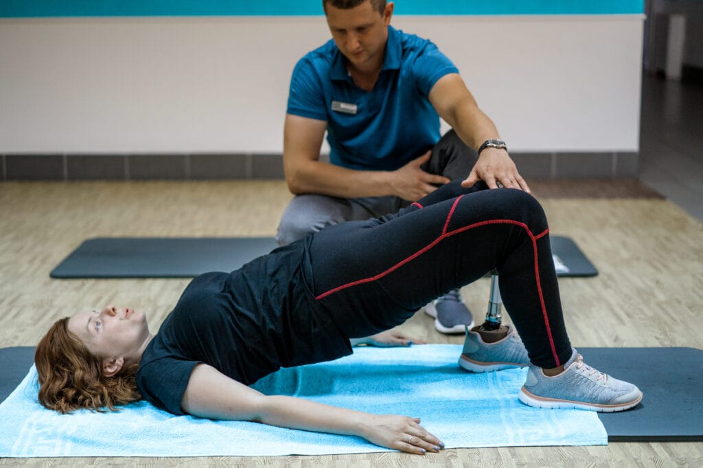 Personal trainer assisting woman with disabilities in her workou personal trainer assisting woman with disabilities her workout sports rehab centre with physiotherapists patients working together towards healing